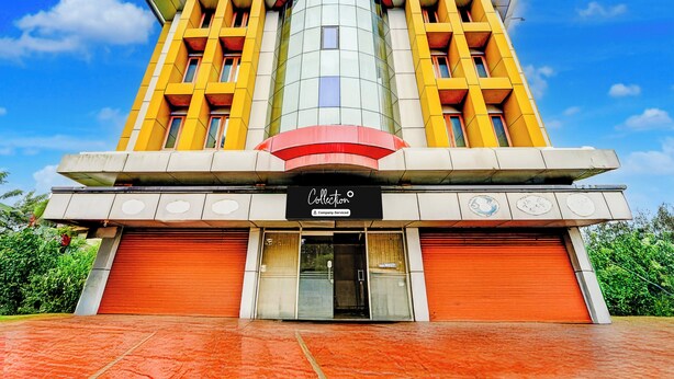 A building with a modern architectural design, featuring a prominent central tower, large windows, and a sign indicating it is a company-serviced location. - Collection O Kottayam Formerly Sap Inn (Kottayam)