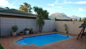 Ein Garten mit Schwimmbad, Kübelpflanzen und Blick auf Berge.