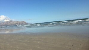 Ein Strand mit blauem Himmel und Bergen im Hintergrund.