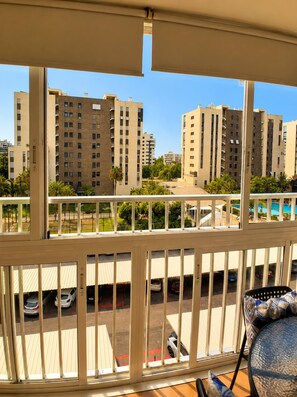 A balcony with a view of high-rise buildings, a parking area with cars, and a pool in the background. - Spacious 2BR Pool Parking Near the Beach (Alicante)