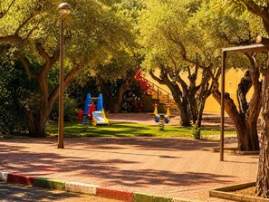 A park with playground equipment, trees, and a lamp post. - Spacious 2BR Pool Parking Near the Beach (Alicante)