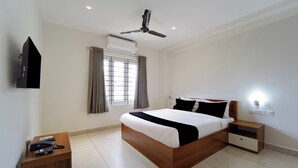 A bedroom with a bed, bedside tables, a ceiling fan, an air conditioning unit, and a window with curtains. - Super Collection O Kottayam (Kottayam)