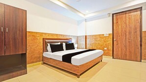 A hotel room with a bed, wooden wardrobe, and a door. - Collection O Uttaranchal University (Dehradun)