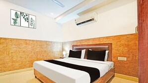 A hotel room with a bed, a ceiling light, an air conditioning unit, and a wall-mounted power outlet. - Collection O Uttaranchal University (Dehradun)