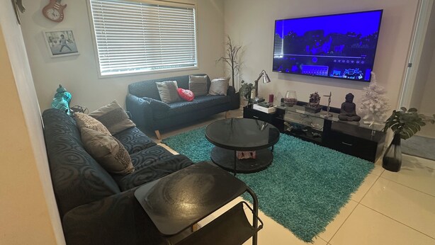 A living room with a sofa, a coffee table, a TV, and a small Buddha statue.