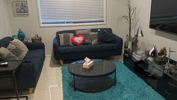 A living room with a sofa, a coffee table, a TV, and a guitar on the wall.