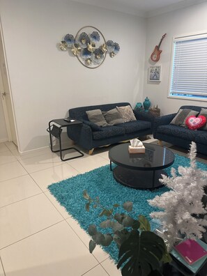 A living room with a blue sofa, a coffee table, and a decorative wall piece.