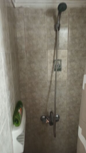 Eine Dusche mit Handbrause und am Wand montiertem Wasserhahn.