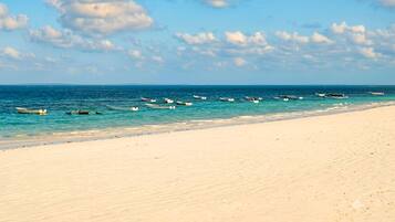 A beach with boats anchored in the water and a sandy shore.