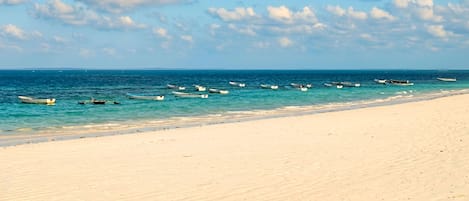 Una playa con barcos anclados en el agua y una orilla arenosa.
