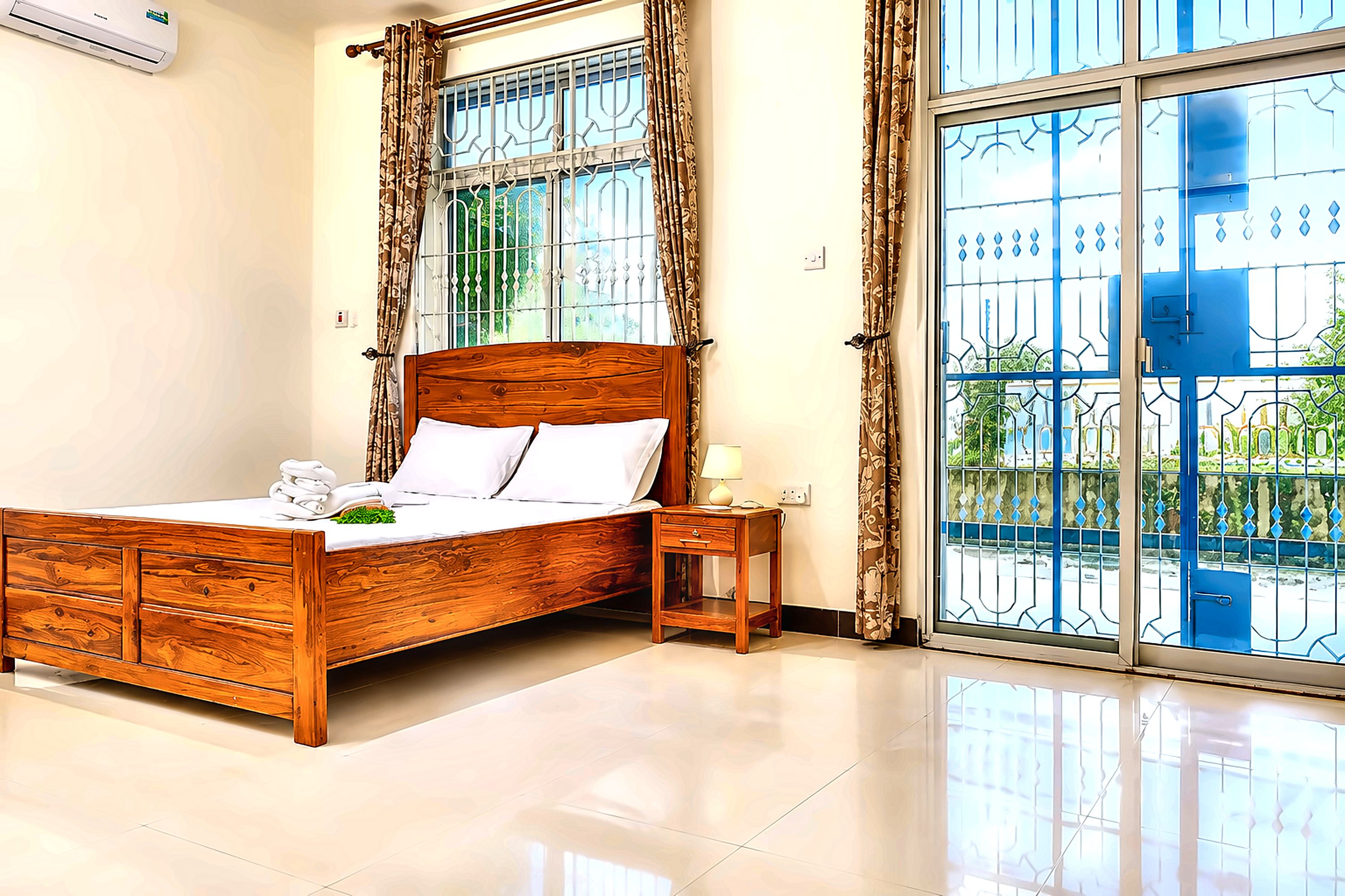 A bedroom with a wooden bed, a bedside table, and a view of a blue gate through a window.