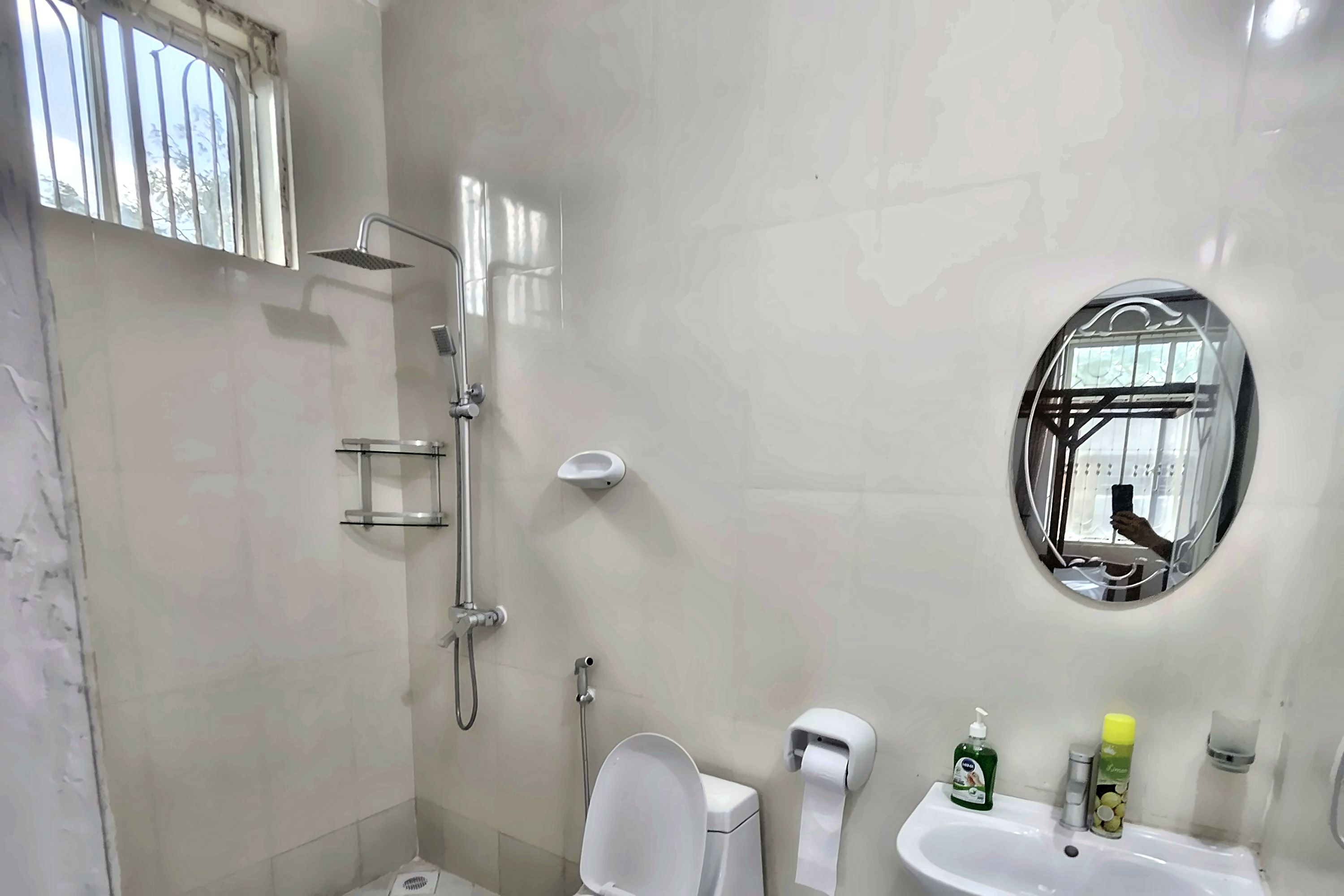 Un baño con ducha, inodoro, lavamanos y espejo.