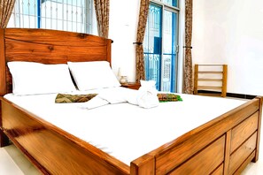 A neatly made bed with white linens and pillows, a wooden headboard, and a nightstand with a lamp. - Exclusive Beachfront Apartment in Uroa, Zanzibar - Ocean Views (Zanzibar, Uroa)