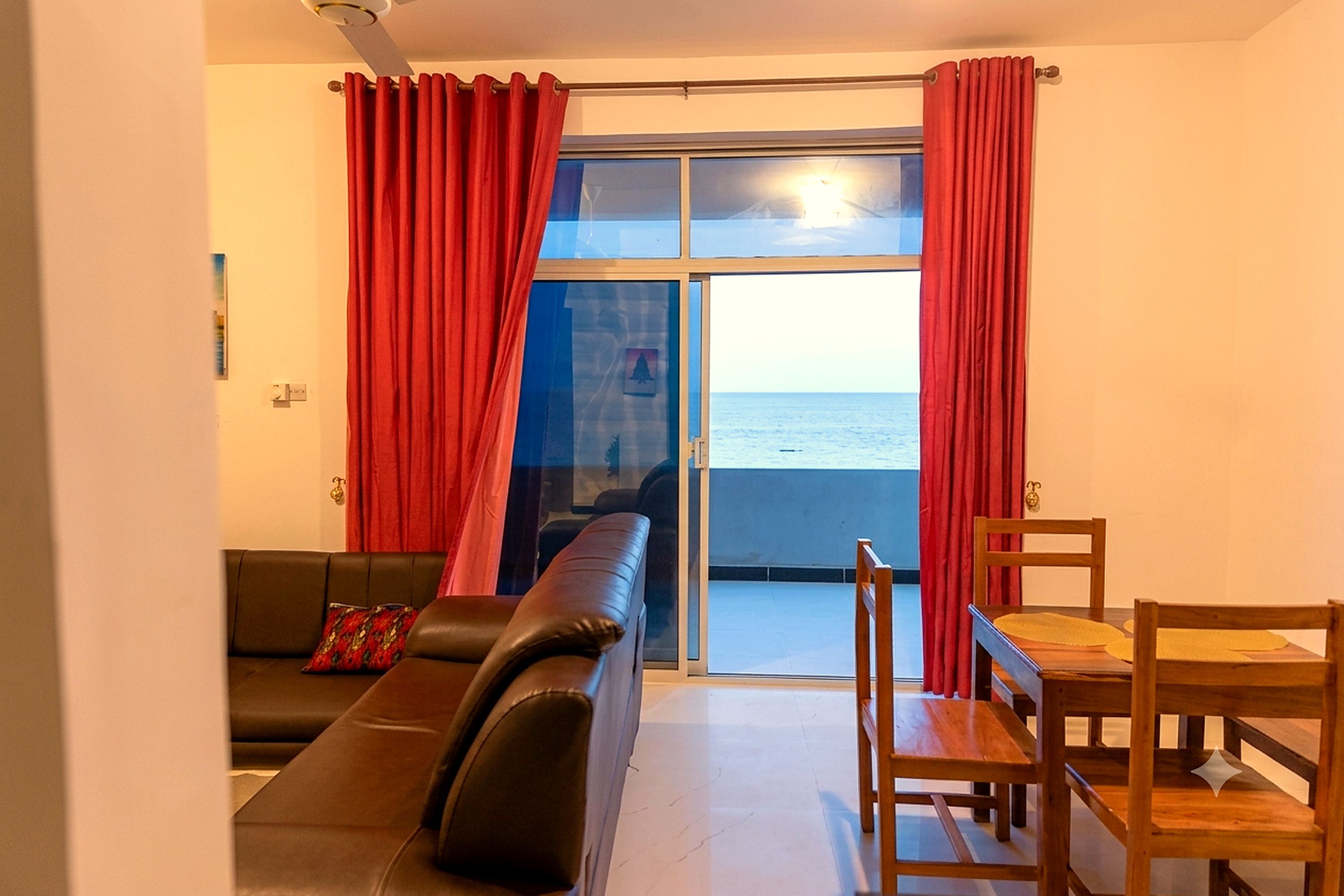 Ein Wohnzimmer mit einer Couch, einem Holztisch und Meerblick durch eine Glastür.