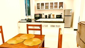 Cozinha compacta com área de refeições, equipada com geladeira, micro-ondas, fogão e armários.