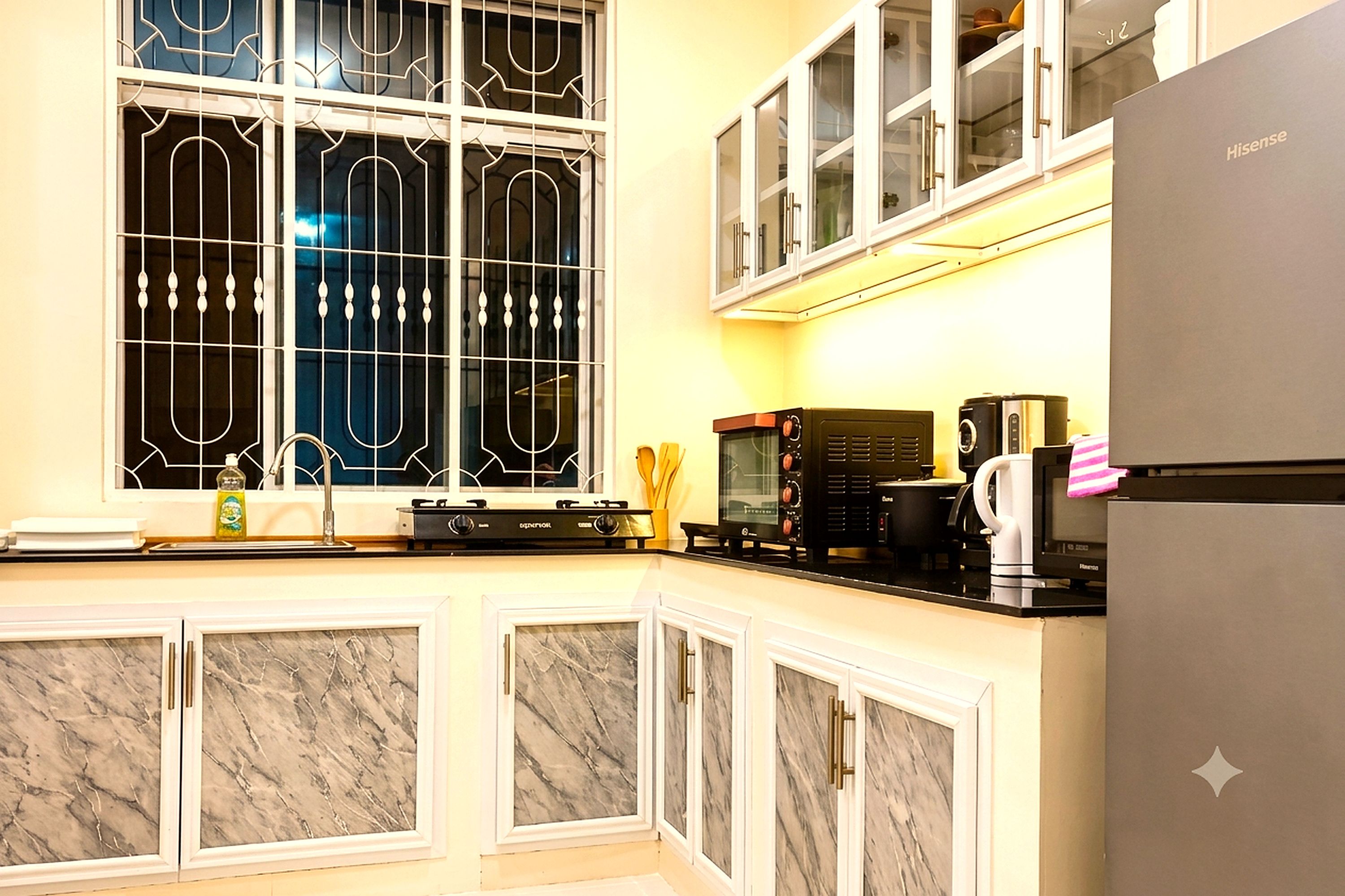 Una cocina con un refrigerador de acero inoxidable, una cafetera y un microondas en la encimera.