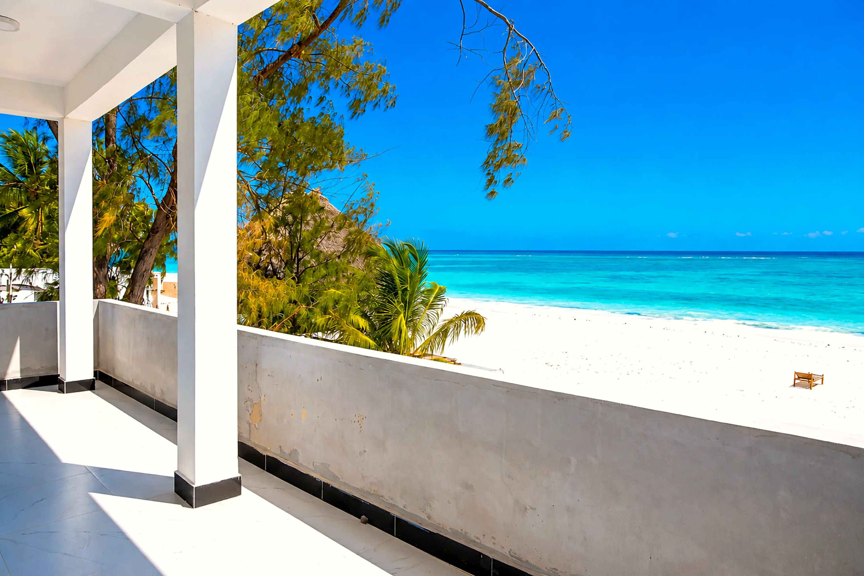 A covered outdoor area with a view of a beach and ocean.