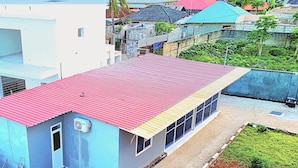 A residential area with a blue building featuring a red roof, surrounded by other colorful houses and greenery. - Private Beachfront Apartment with Ocean Views in Zanzibar (Zanzibar, Uroa)