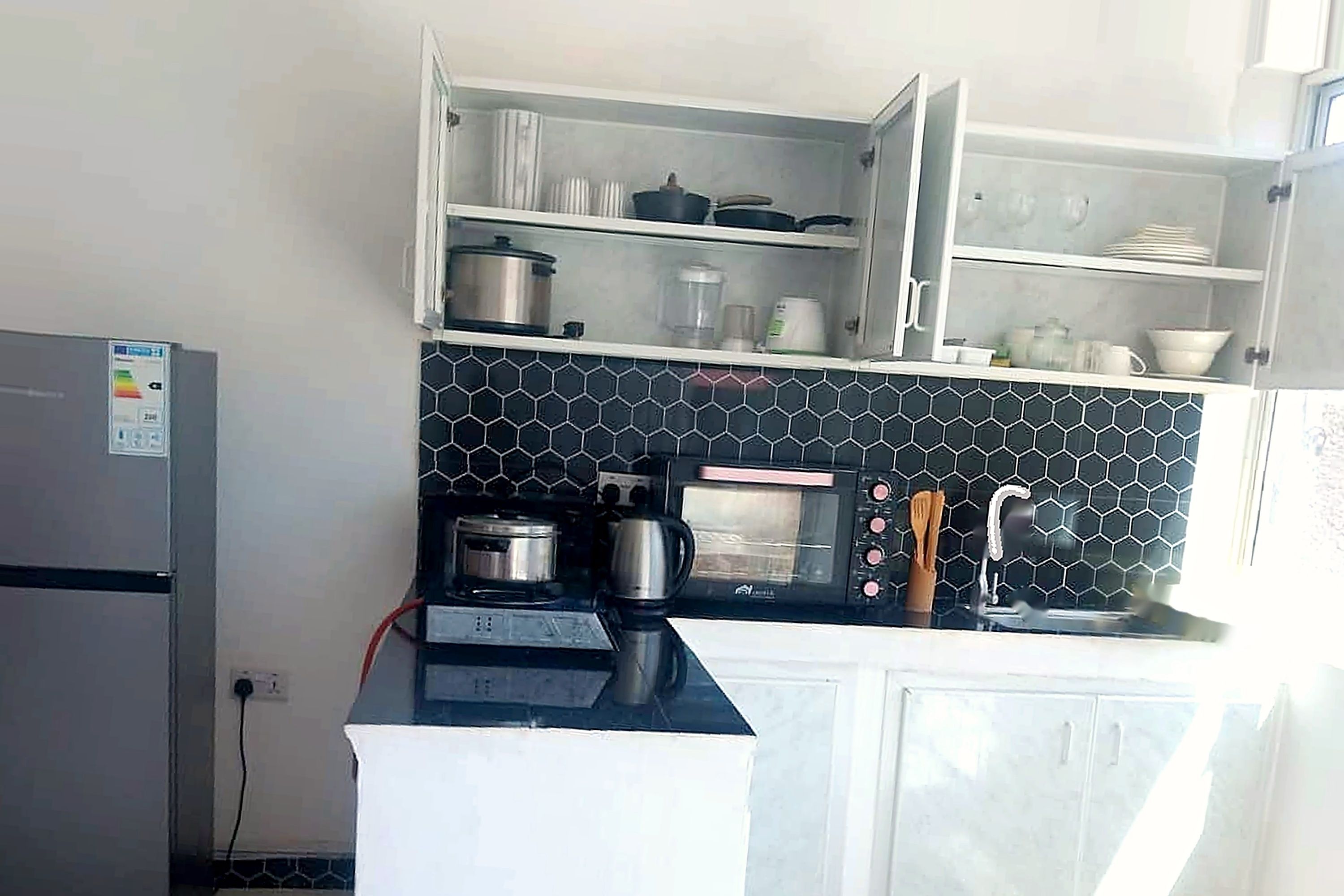 Una cocina compacta equipada con refrigerador, microondas, estufa y pileta.
