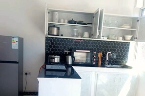 Une cuisine compacte équipée d’un réfrigérateur, d’un four à micro-ondes, d’une cuisinière et d’un évier.