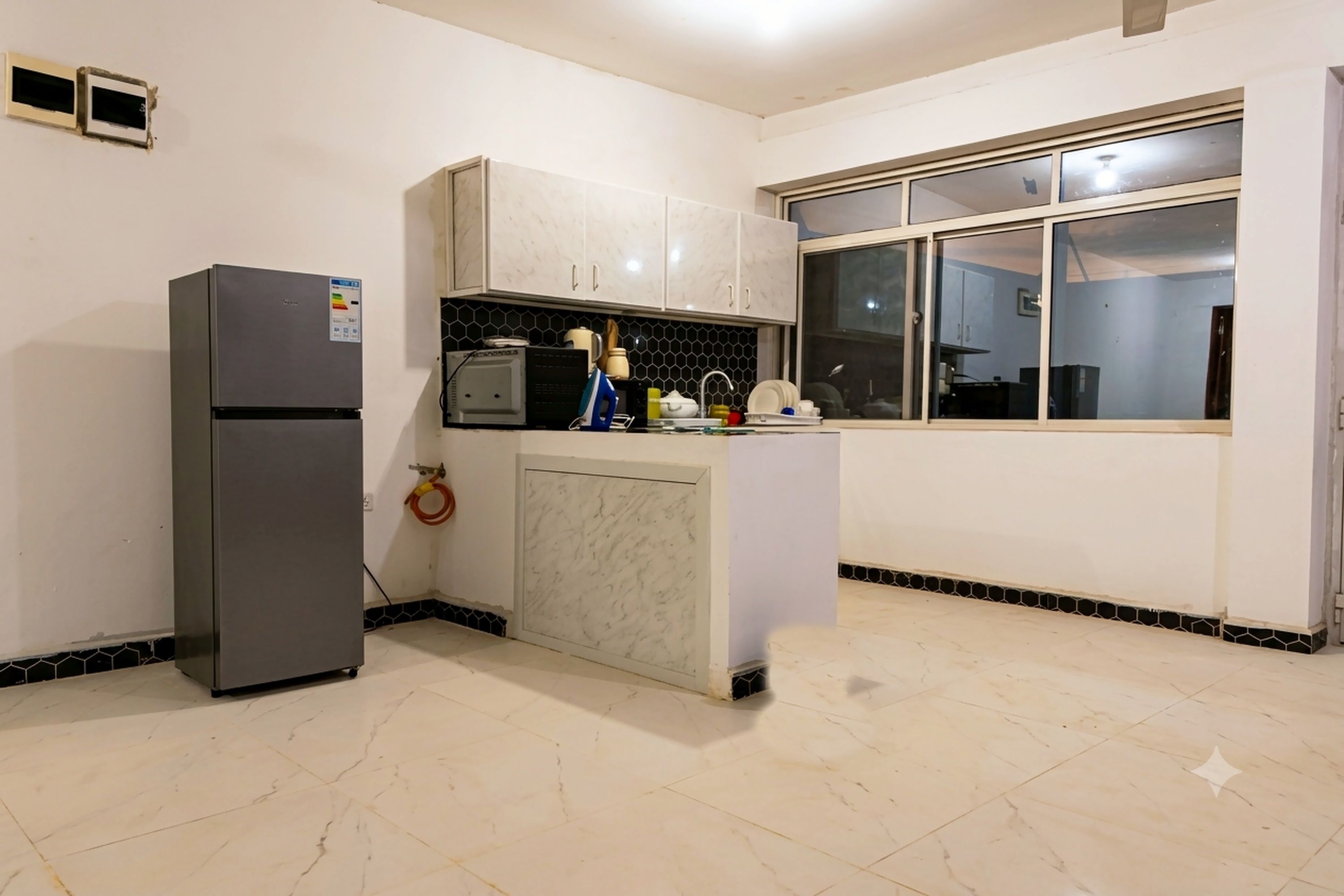 Cocina compacta con refrigerador, microondas y pileta.