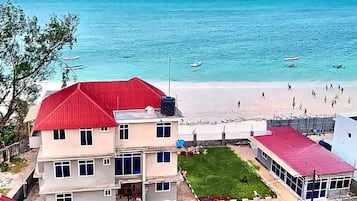 Une propriété située en bord de mer, avec un bâtiment à toit rouge, une pelouse et une vue sur l’océan.