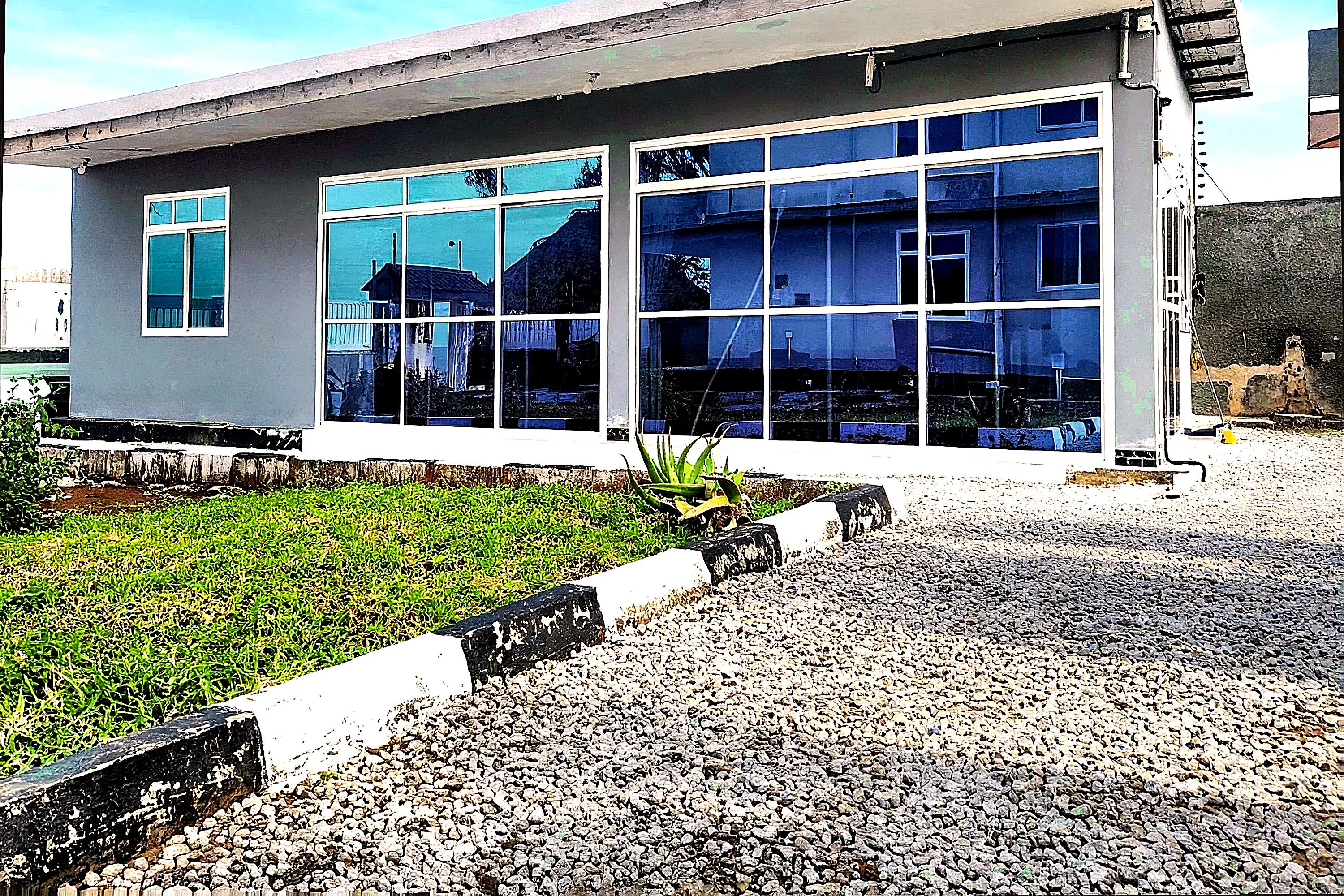A modern building with large windows and a gravel driveway.
