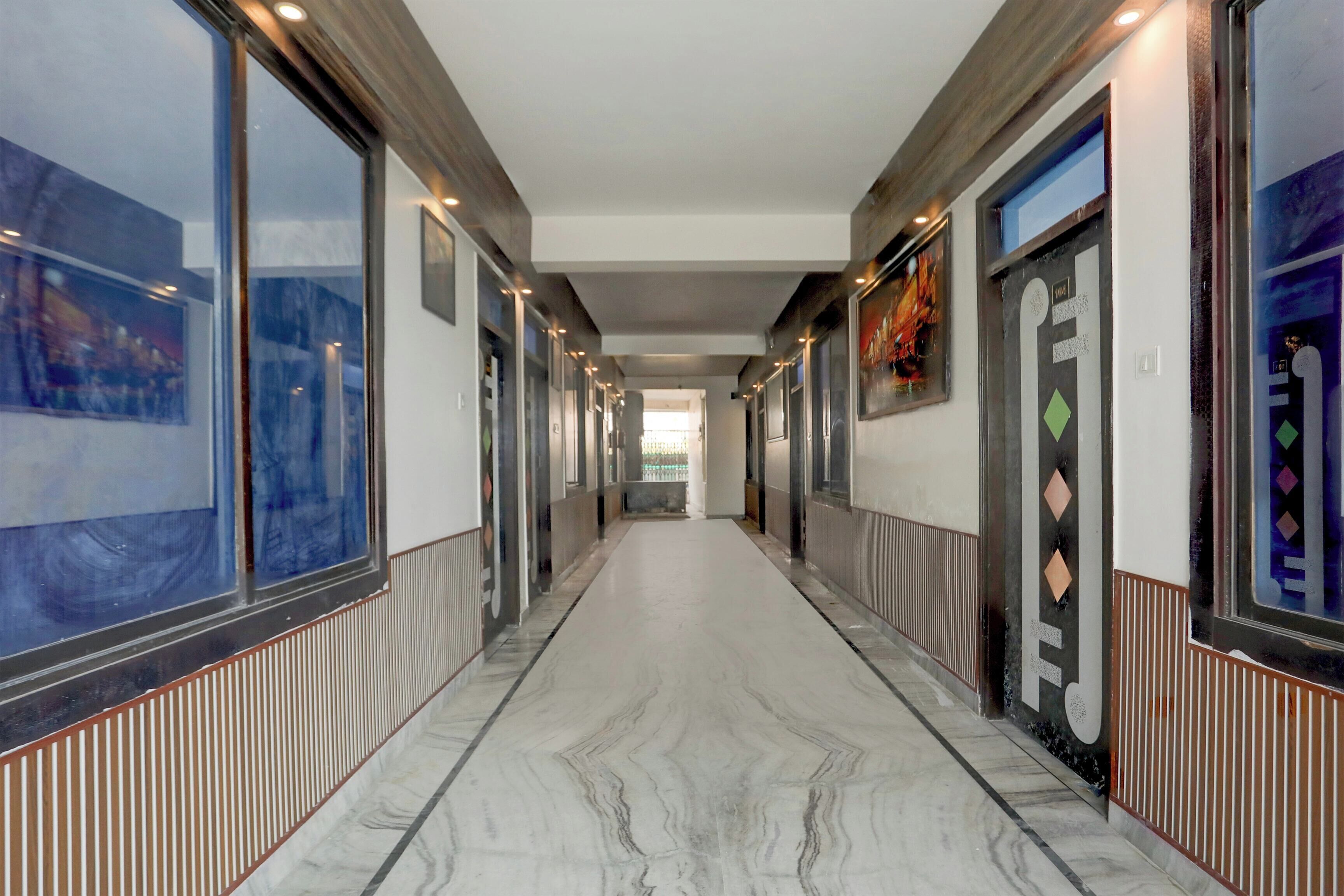 A corridor with a marble floor, flanked by walls with artwork and doors.