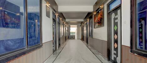 A corridor with a marble floor, flanked by walls with artwork and doors.