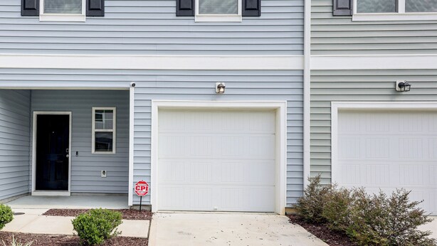 A two-story residential building with a garage door, a security camera, and a 'Warning: CP Security' sign. - 3 Mi to Wilson! Sleek Townhome w/ Screened Porch (Wilson)
