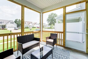 Ein überdachter Balkon mit Korbmöbeln und Blick auf eine Wohngegend.