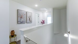 A staircase with a white handrail and a wall-mounted light fixture. - 3 Mi to Wilson! Sleek Townhome w/ Screened Porch (Wilson)