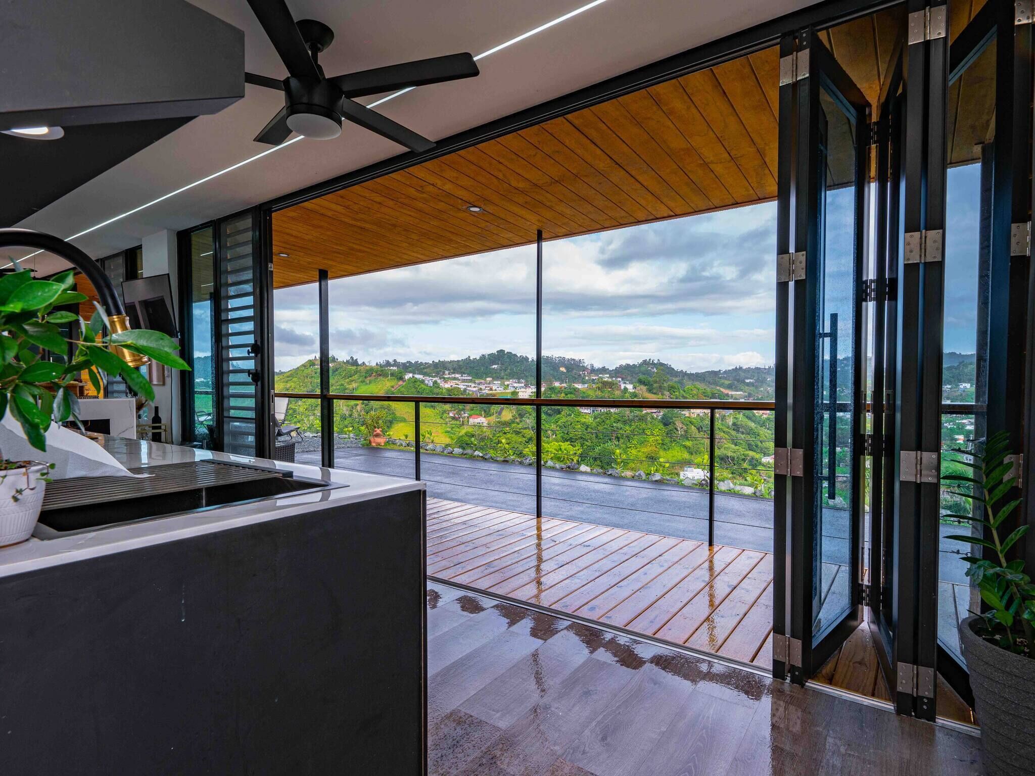 Une cuisine moderne offrant une vue sur un paysage verdoyant grâce à de grandes portes vitrées.