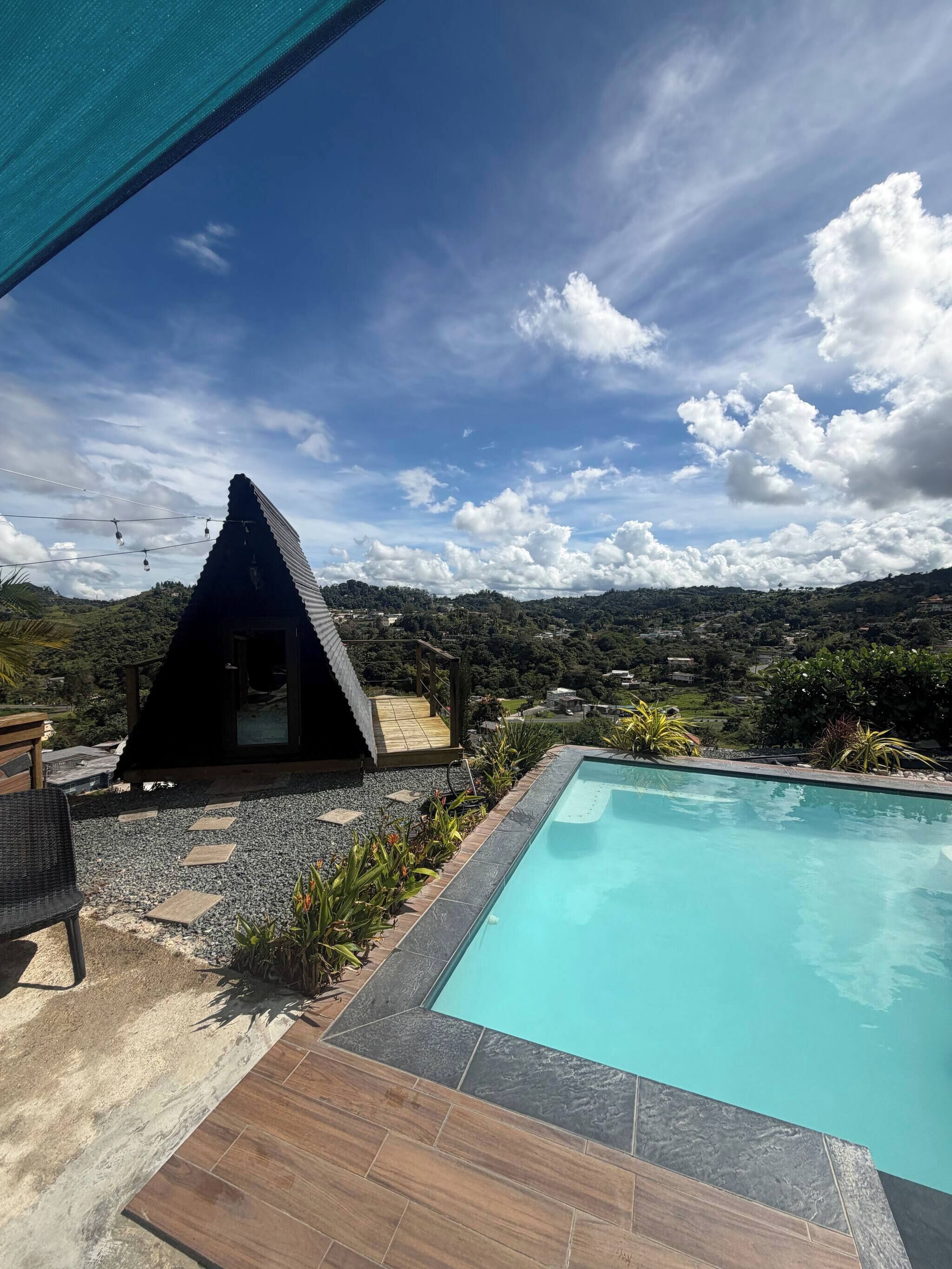A pool area with a clear view of the surrounding landscape, a small structure, and a wooden deck.
