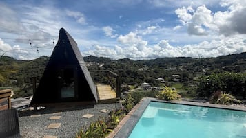 A pool area with a clear view of the surrounding landscape, a small structure, and a wooden deck.
