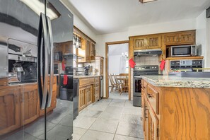 A kitchen with wooden cabinets, a stainless steel refrigerator, a microwave, and a stove. - Private Yard & Patio! Overland Park Group Getaway (Overland Park)