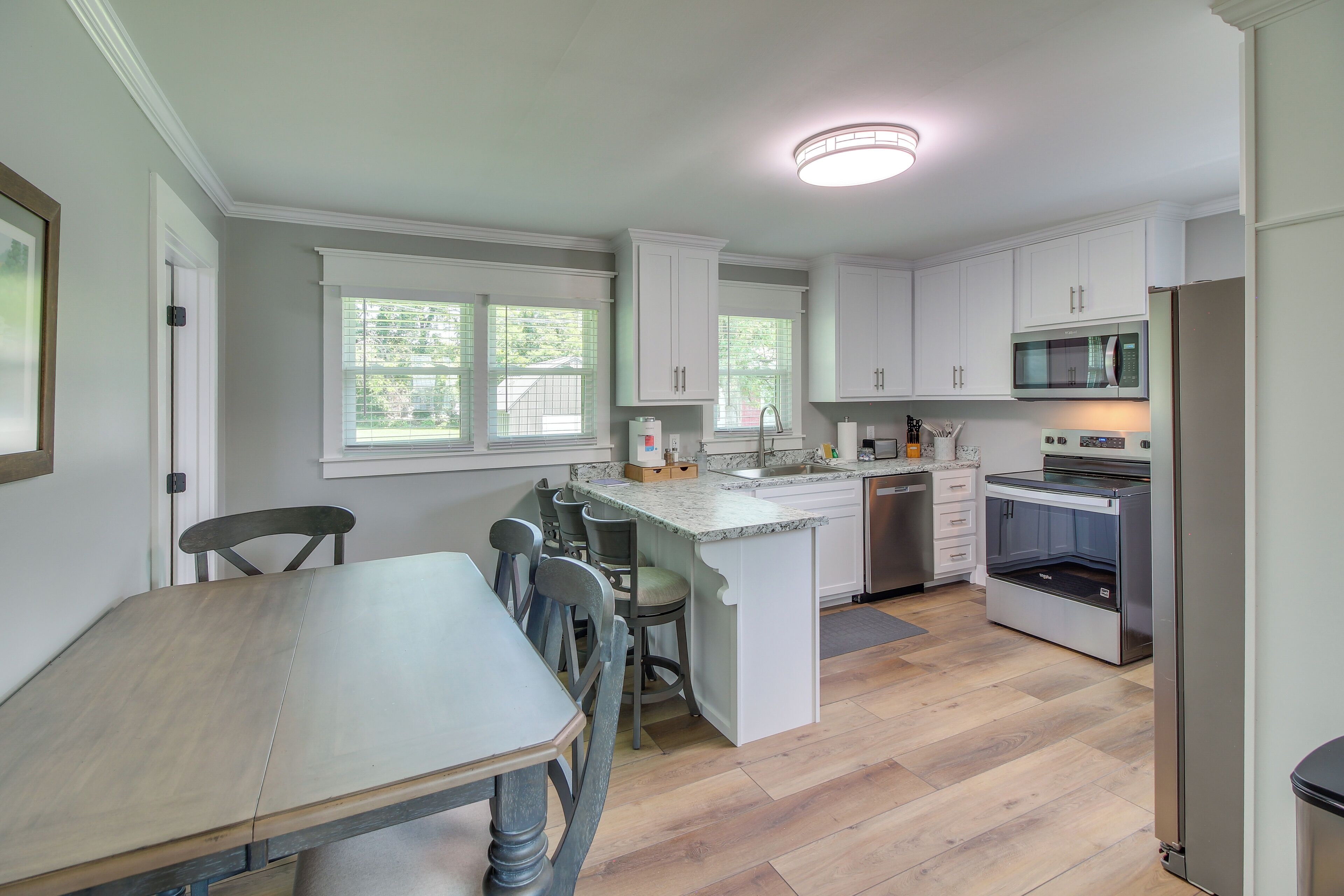A modern kitchen with white cabinetry, a central island, and a dining area with a wooden table and chairs.
