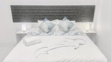 Una cama con cubre cama blanco, dos mesitas de noche con lámparas y un cabecero con diseño texturizado.
