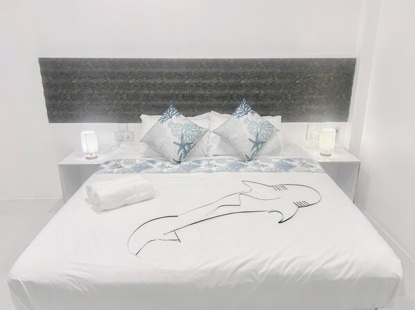 A bed with a white cover, two nightstands with lamps, and a headboard with a textured design.