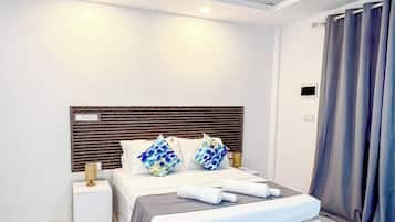 Une chambre d’hôtel moderne avec un grand lit, un ventilateur de plafond, une lampe de chevet et une fenêtre avec des rideaux.