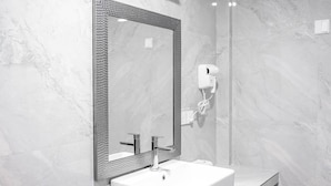A modern bathroom with a rectangular mirror, a white sink, and a handheld hair dryer mounted on the wall. - Aquatic Mathiveri (Alifu Alifu Mathiveri)