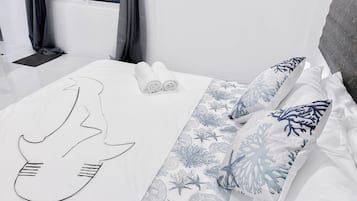 A hotel room with a bed, a window with curtains, a bedside table, and a wall socket.