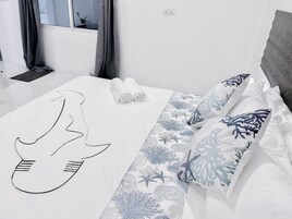A hotel room with a bed, a window with curtains, a bedside table, and a wall socket.