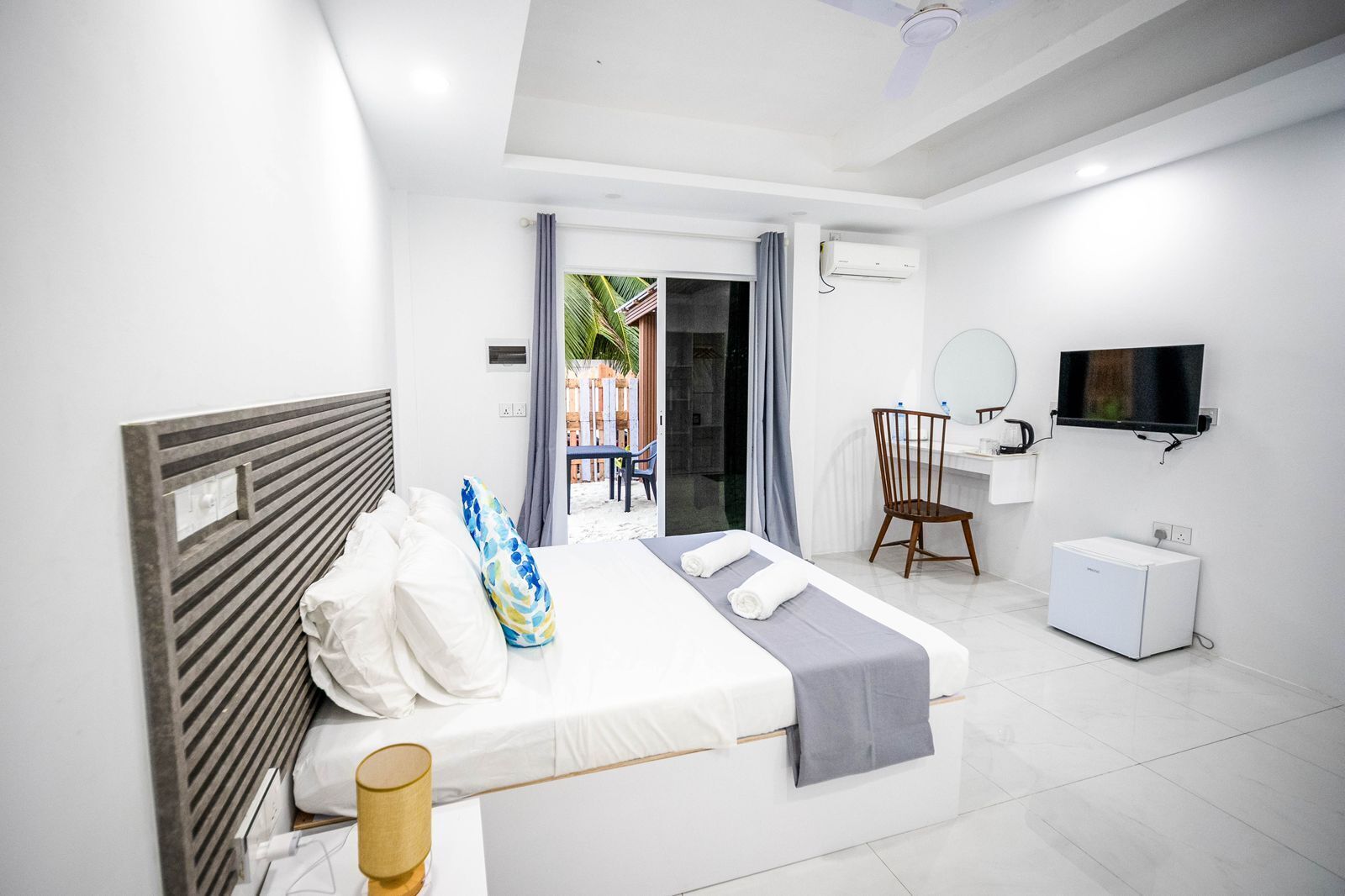 Una habitación de hotel con una cama, un escritorio, una silla, un televisor y un equipo de aire acondicionado.