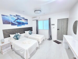 Habitació d'hotel amb dos llits, una taula de nit, una finestra amb cortines i una obra d'art a la paret.