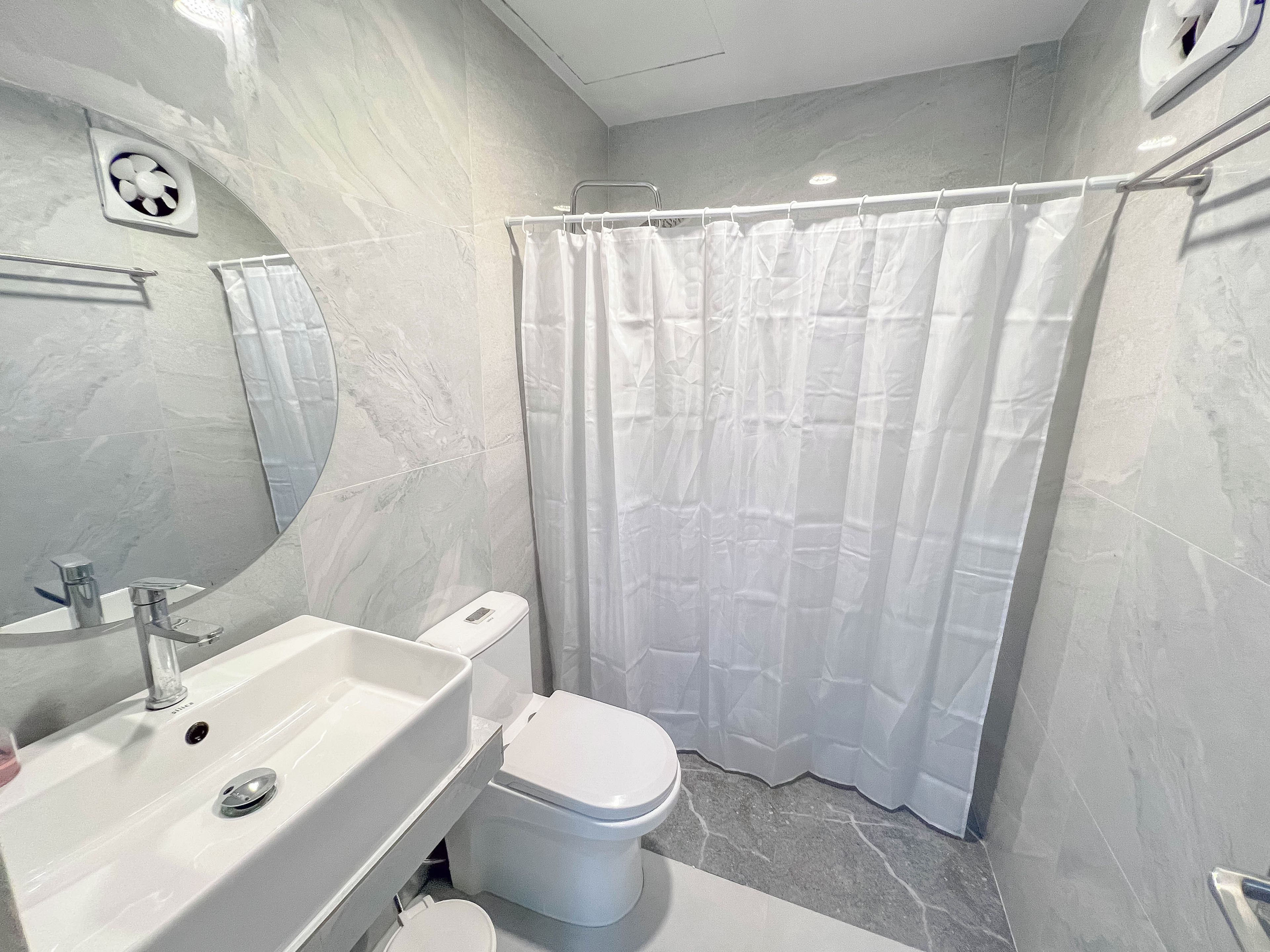Une salle de bain avec un lavabo blanc, des toilettes et un rideau de douche.