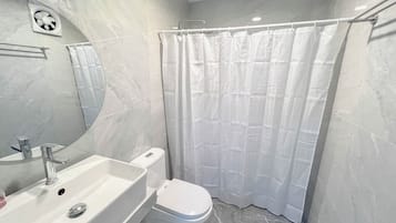 Une salle de bain avec un lavabo blanc, des toilettes et un rideau de douche.