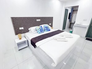 A modern hotel room with a large bed, a bedside table with a lamp, and a view of the bathroom.