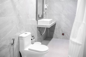 Un baño moderno con inodoro, lavamanos y zona de ducha.