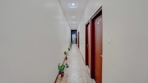Un pasillo con plantas en macetas, puertas de madera y suelo de baldosas.
